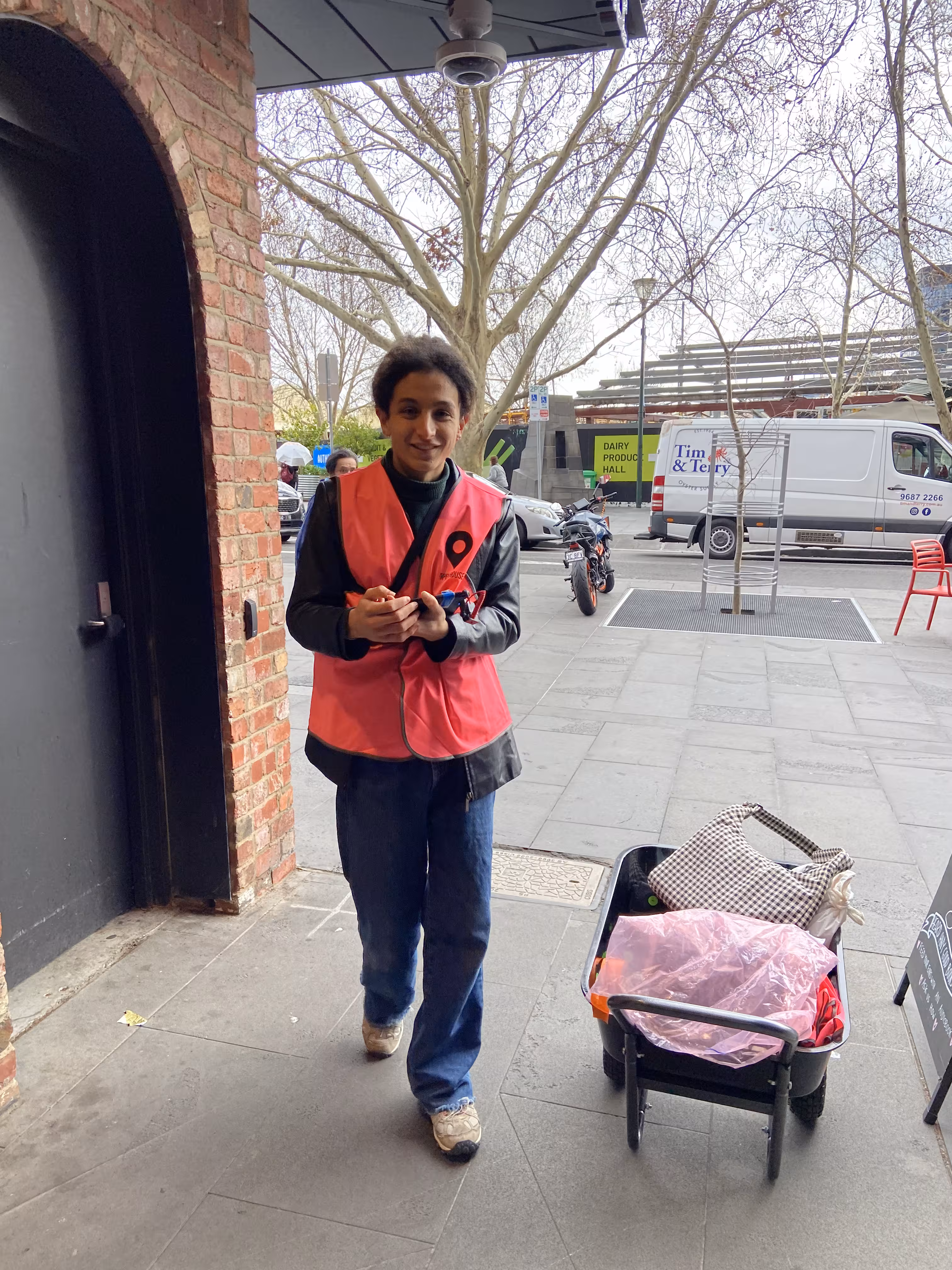 Me dressed in a pink hi-vis vest, holding an iPad with a wheelbarrow